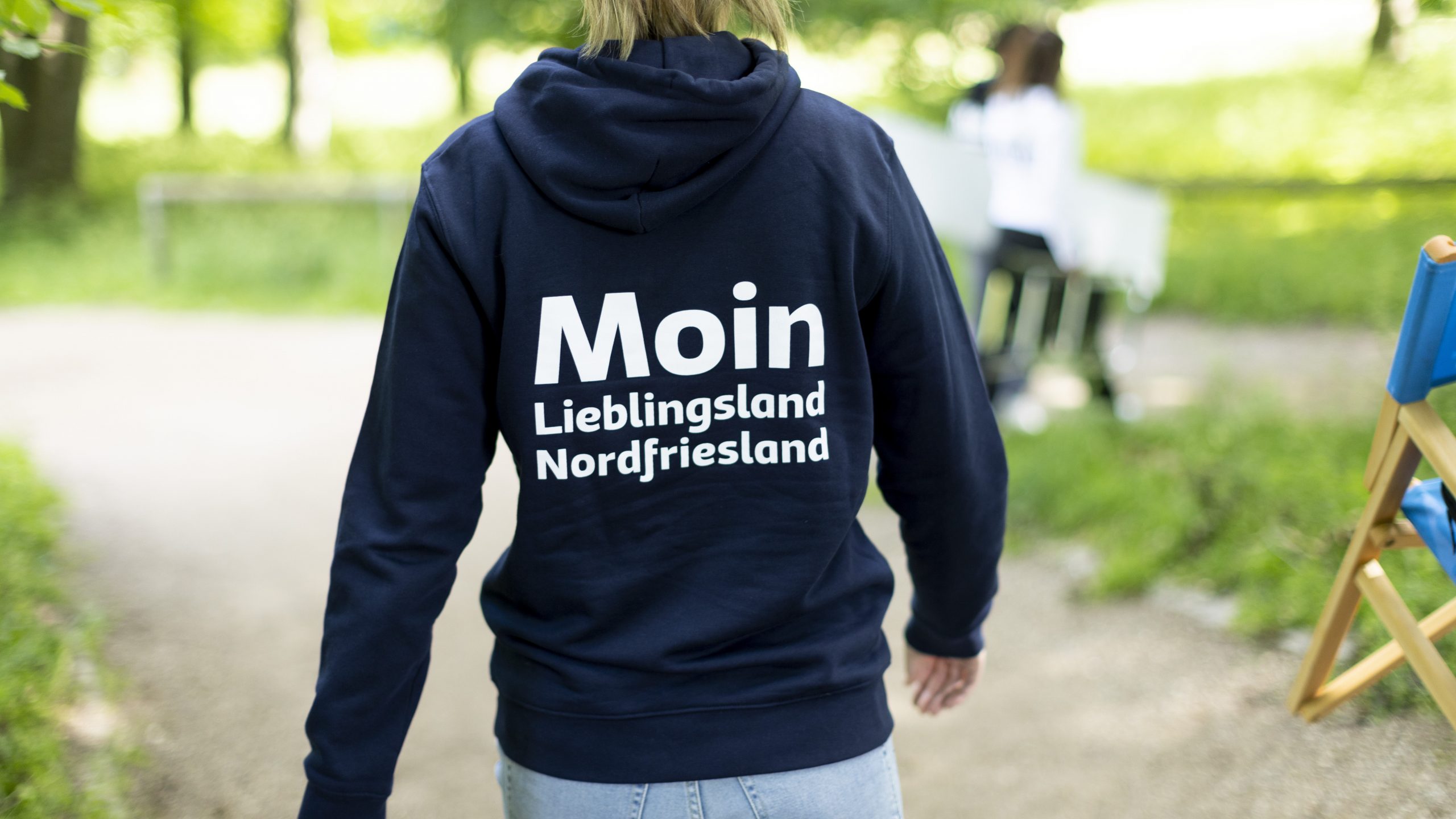Rückenansicht einer Mitarbeiterin der Wirtschaftsförderung Nordfriesland. Sie trägt einen dunkelblauen Kapuzenpullover mit der Aufschrift 